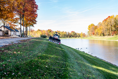 Ventrac aerating park embankment by pond